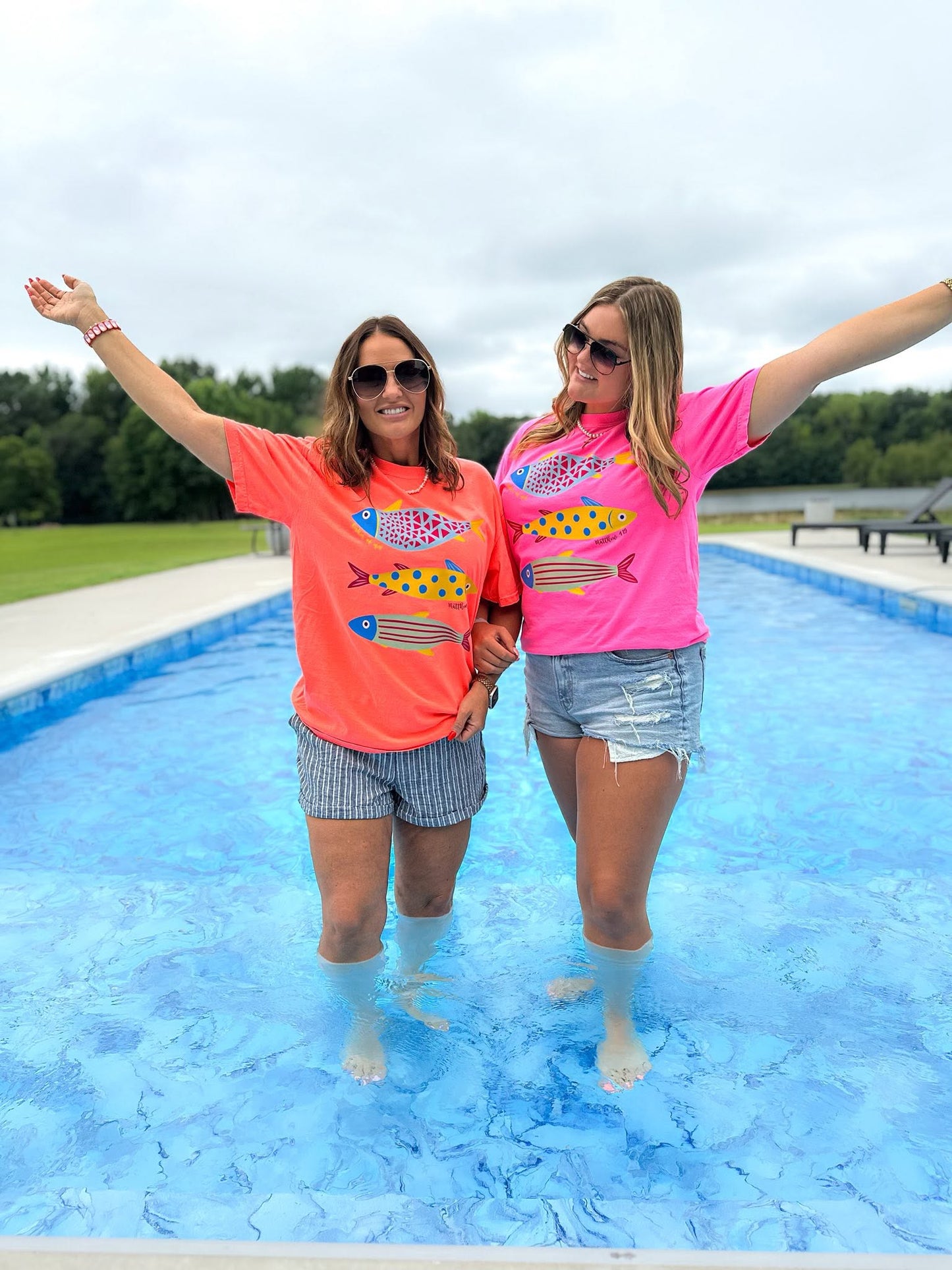 woman wearing a neon pink fisher of men christian comfort colors t-shirt by a swimming pool